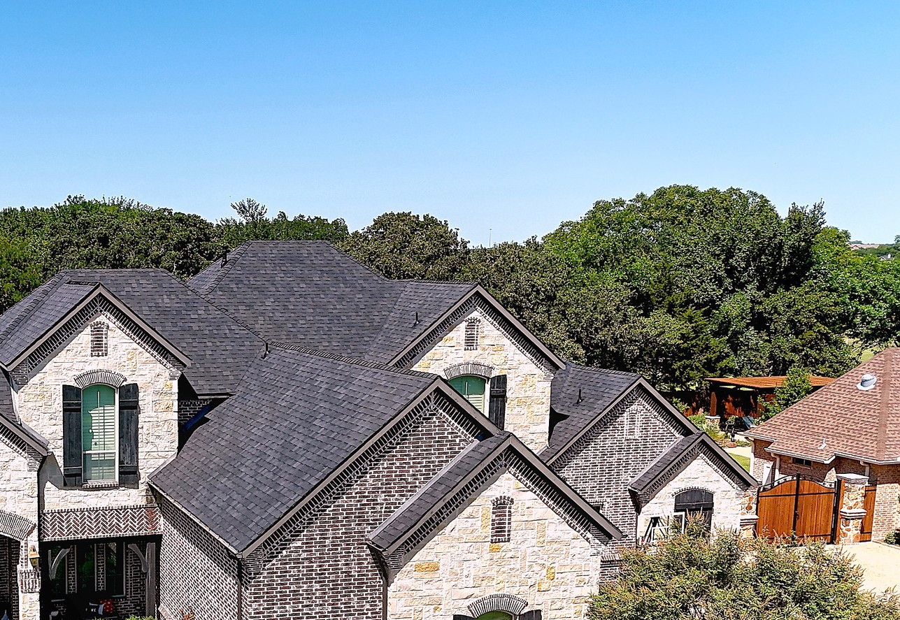 A brick and stone two-story home with a new dark architectural shingle roof