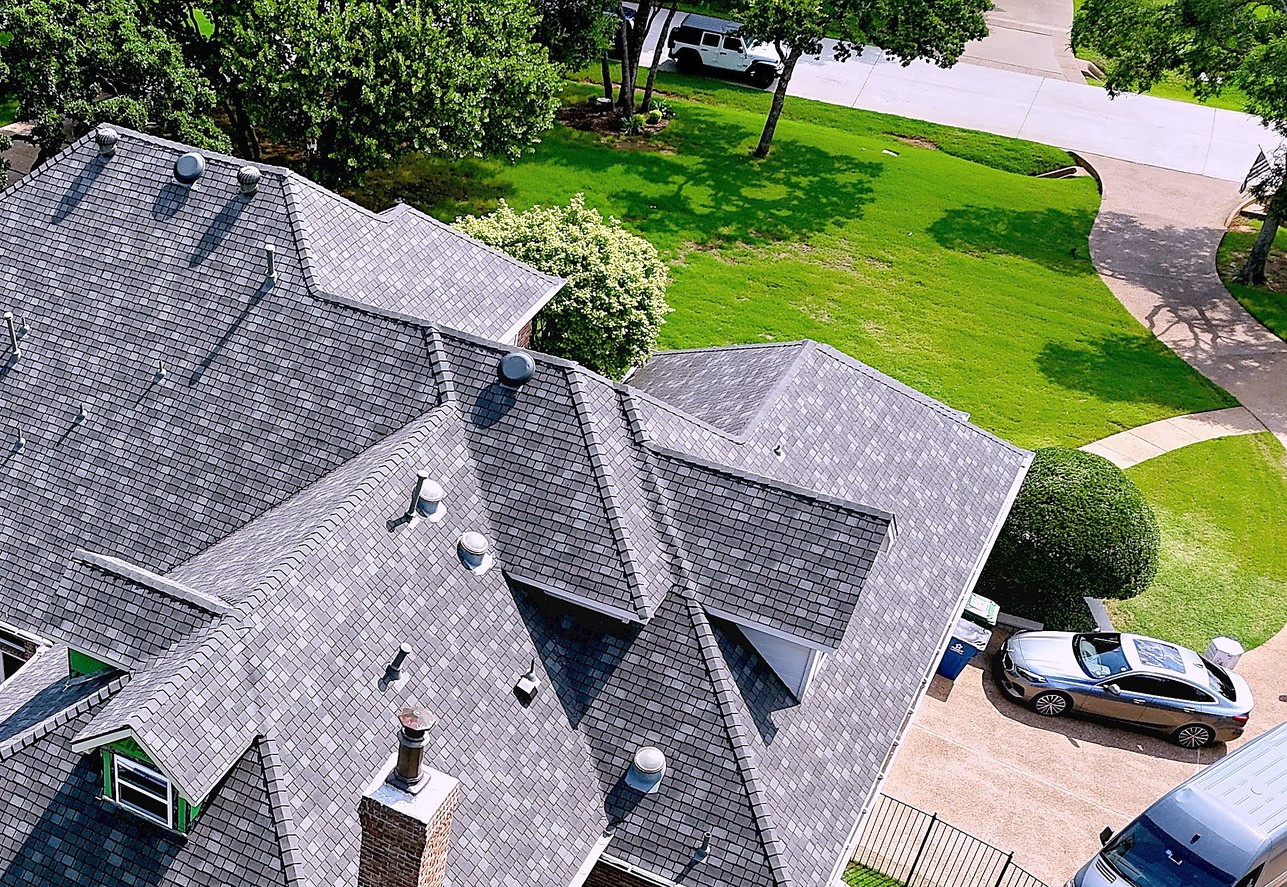 A single story brick home with a new grey shingle roof and a circular drive