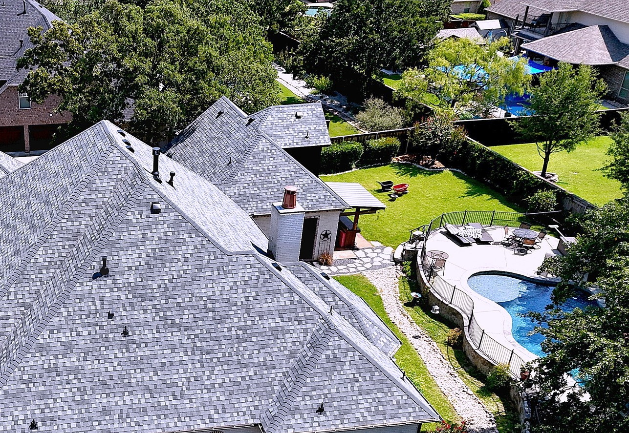 A painted brick ranch home with a new grey shingle roof and a pool